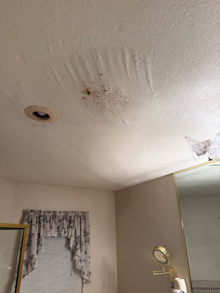 Water-stained, bubbling bathroom ceiling caused by a roof leak in a Raton, NM home