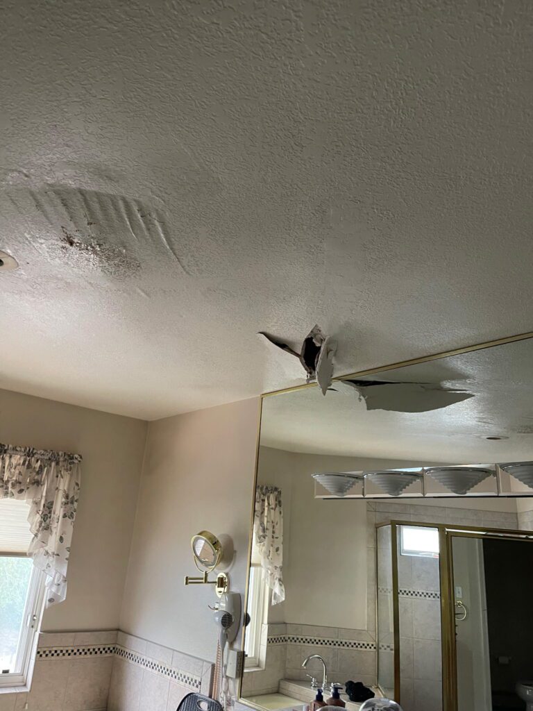 Bathroom ceiling that broke open after a long-term roof leak in a Raton, NM home