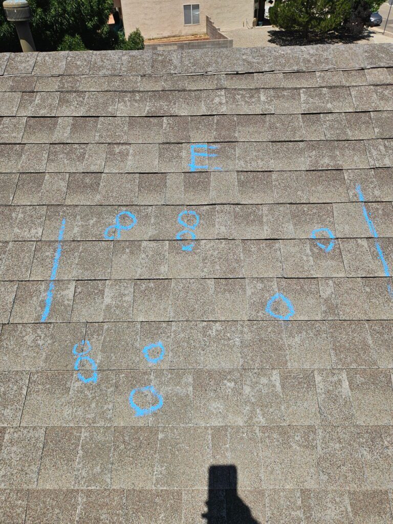 Asphalt shingle test square with hail hits circled in blue chalk on a Raton, NM roof